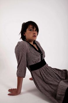 young brunette woman in dress sitting on the ground with boots