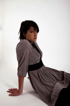 young brunette woman in dress sitting on the ground with boots