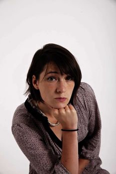 young woman looking ahead with hand under her face isolated in studio