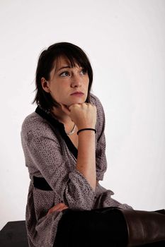 young woman looking ahead with hand under her face isolated in studio