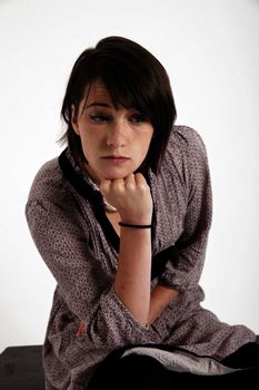 young woman looking ahead with hand under her face isolated in studio