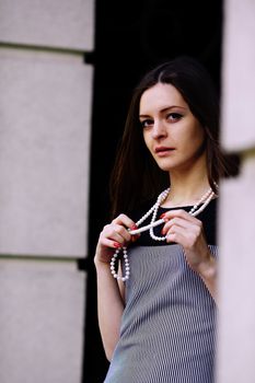 Attractive girl in a beautiful dress, holding in hands white beads