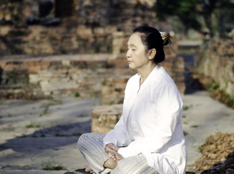 Asian woman meditating yoga in ancient buddhist temple 