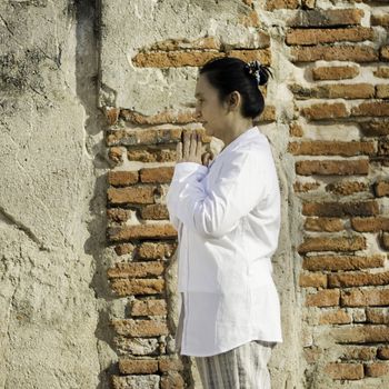 Thai woman with typical welcome expression againts brick background