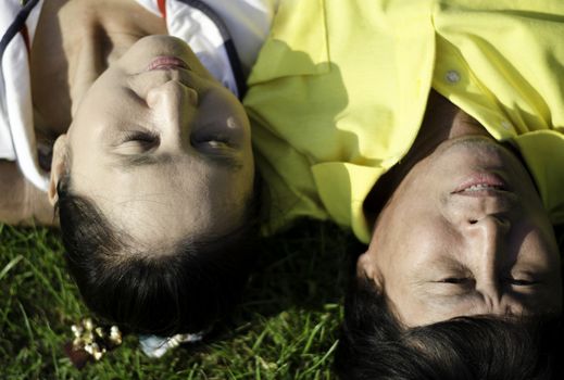 Closeup of senior couple lying on the grass with heads together 