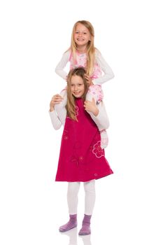 Young girl giving piggyback ride to her sister. Isolated on white background.