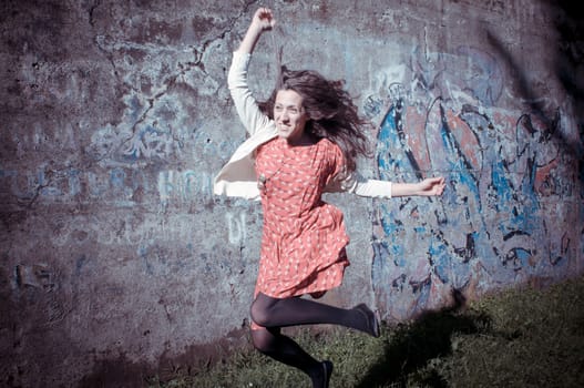happy eastern vintage hipster woman jumping in the park