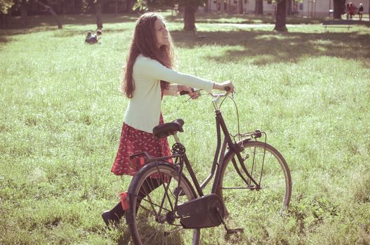 vintage eastern hipster woman with bike in the park