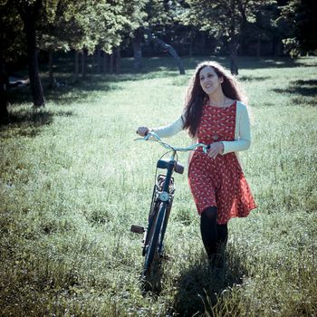 vintage eastern hipster woman with bike in the park