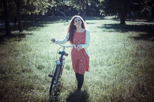 vintage eastern hipster woman with bike in the park