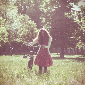 vintage eastern hipster woman with bike in the park