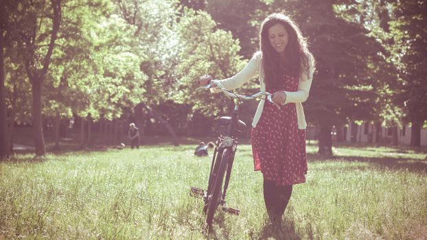 vintage eastern hipster woman with bike in the park