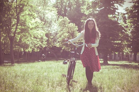 vintage eastern hipster woman with bike in the park