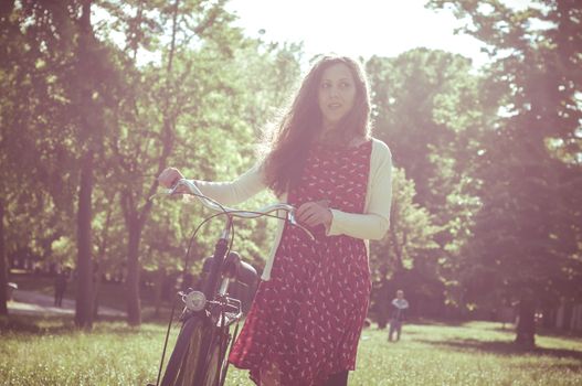 vintage eastern hipster woman with bike in the park