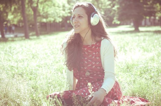 vintage hipster eastern woman with headphones in the park
