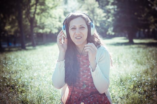 vintage hipster eastern woman with headphones in the park