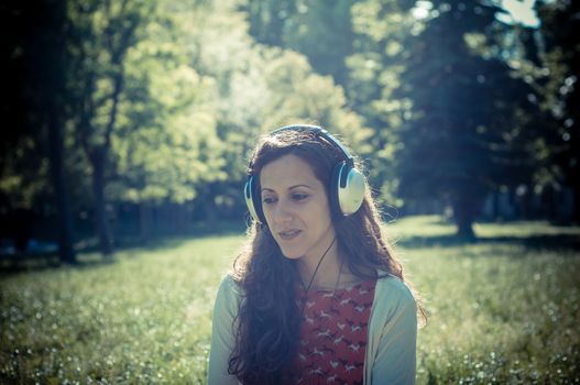 vintage hipster eastern woman with headphones in the park