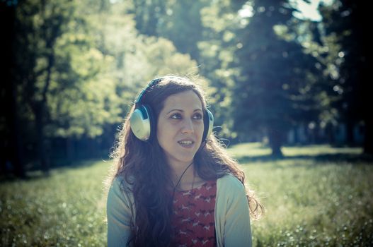 vintage hipster eastern woman with headphones in the park