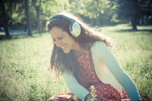 vintage hipster eastern woman with headphones in the park