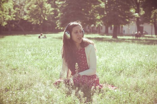 vintage hipster eastern woman with headphones in the park