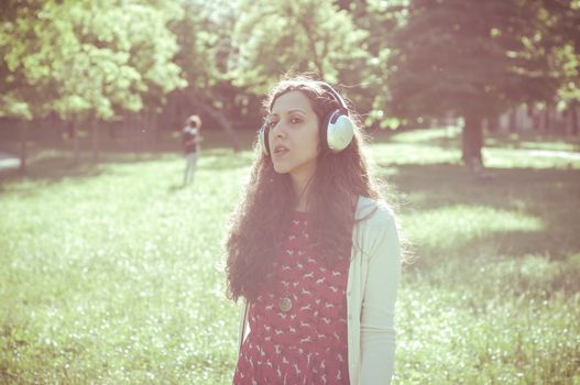 vintage hipster eastern woman with headphones in the park