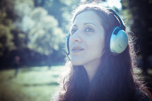 vintage hipster eastern woman with headphones in the park