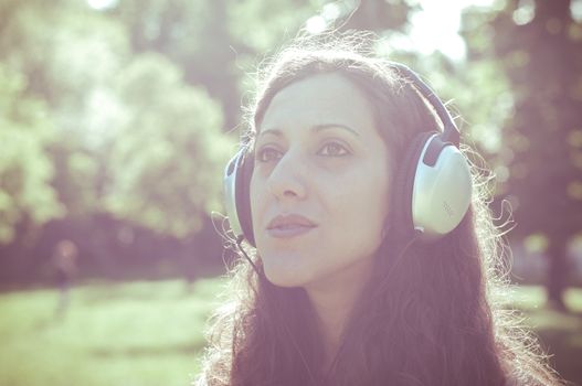vintage hipster eastern woman with headphones in the park