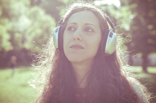 vintage hipster eastern woman with headphones in the park