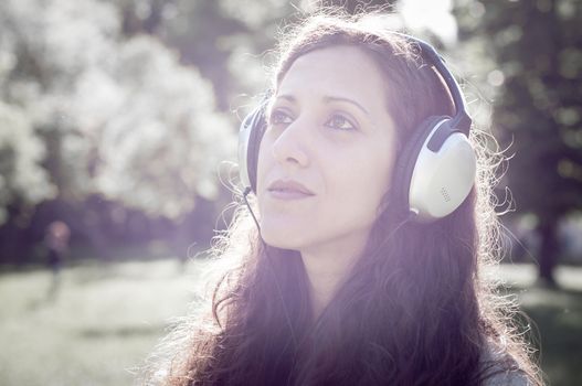 vintage hipster eastern woman with headphones in the park