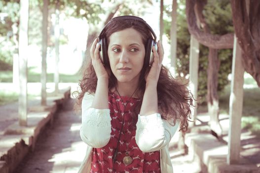 vintage hipster eastern woman with headphones in the park