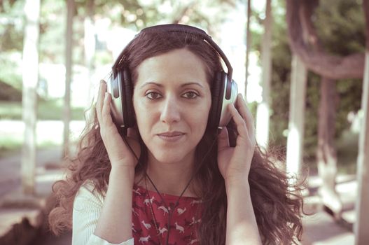 vintage hipster eastern woman with headphones in the park