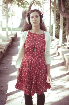 vintage hipster eastern woman with headphones in the park