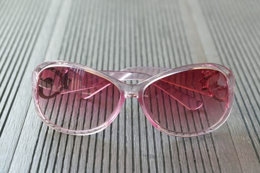 Pink sunglasses put on the wooden table
