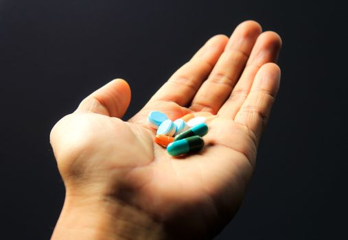 Closeup Pills in hand on black background