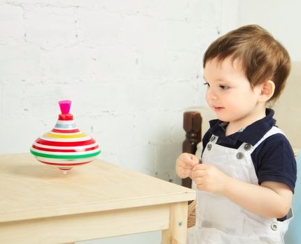 little boy playing with whirligig on a table