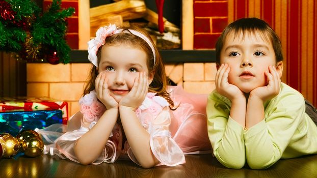 two beautiful child lying near christmas tree