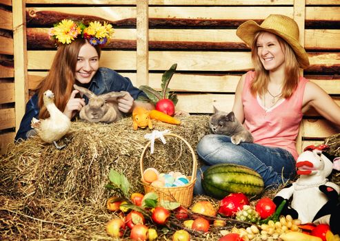 two girl with rabbit, cat and harvest on hayloft at summer day