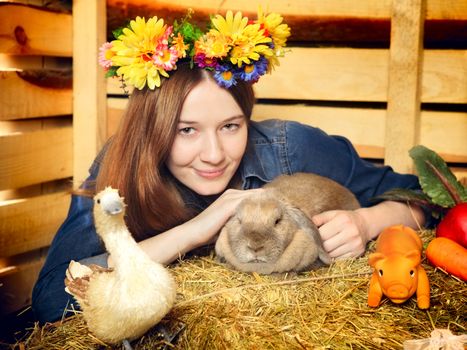 beautiful girl with rabbit on hayloft at summer day