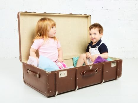 little boy and girl sitting in suitcase and playing