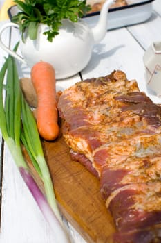 Raw pork ribs seasoned for baking on a wooden board