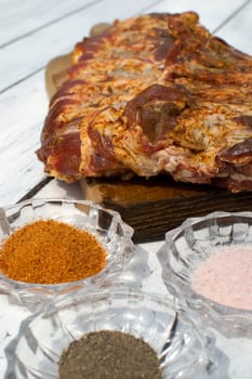 Raw pork ribs seasoned for baking on a wooden board