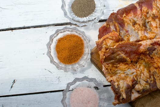 Raw pork ribs seasoned for baking on a wooden board