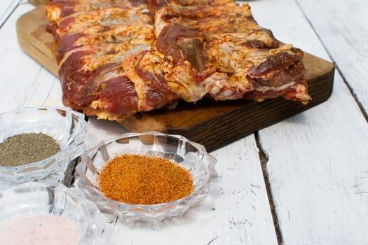 Raw pork ribs seasoned for baking on a wooden board