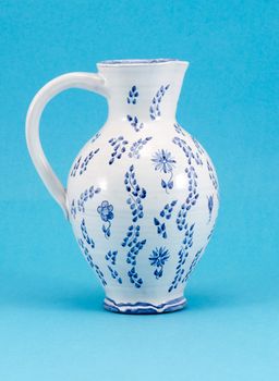big hand made aged jug jar with art paint ornaments on blue background.