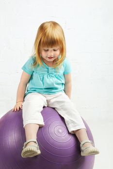 beautiful little girl sitting on big ball