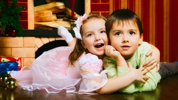 two beautiful child lying near christmas tree