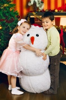 two beautiful child and toy snowman near christmas tree