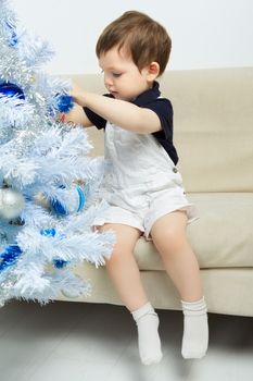 beautiful happy small kid decorate christmas tree