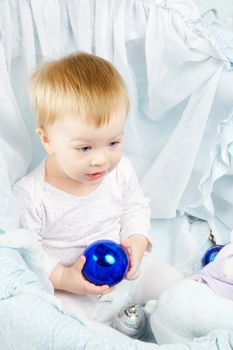 baby in cradle playing with christmas ball