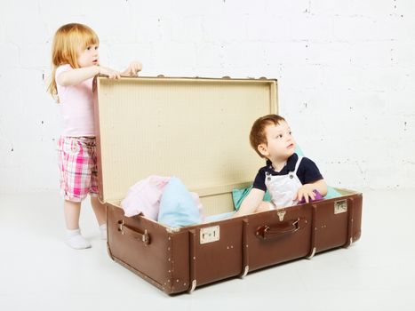 little boy and girl sitting in suitcase and playing